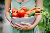 Close-up of a woman holding a bowl of freshly harvested vegetables