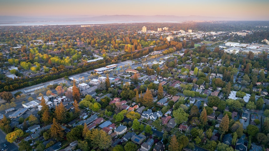 Sprawling suburbia with a bay and mountains in the background.