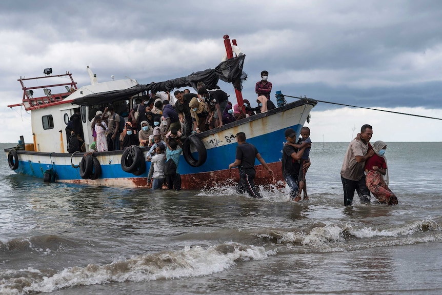 Local fisherman help ethnic-Rohingya people as they arrive on a beach in Aceh.