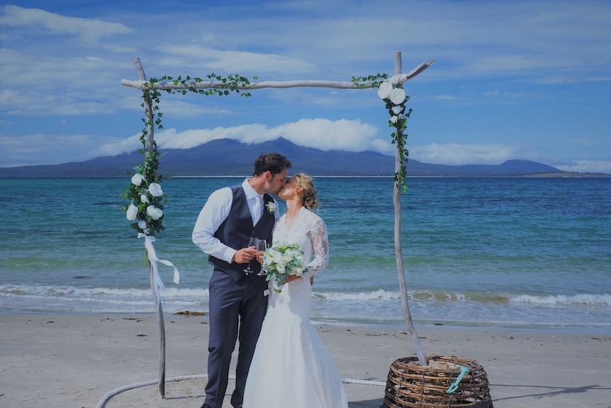 Naomi Wisby and husband Brody Corbett on a beach on their wedding day.