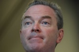 Mr Pyne mouth is closed, and he's looking to the left of frame. He's wearing a blue tie.