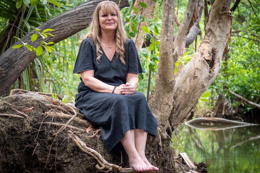 Woman sitting on the bank of a creek.