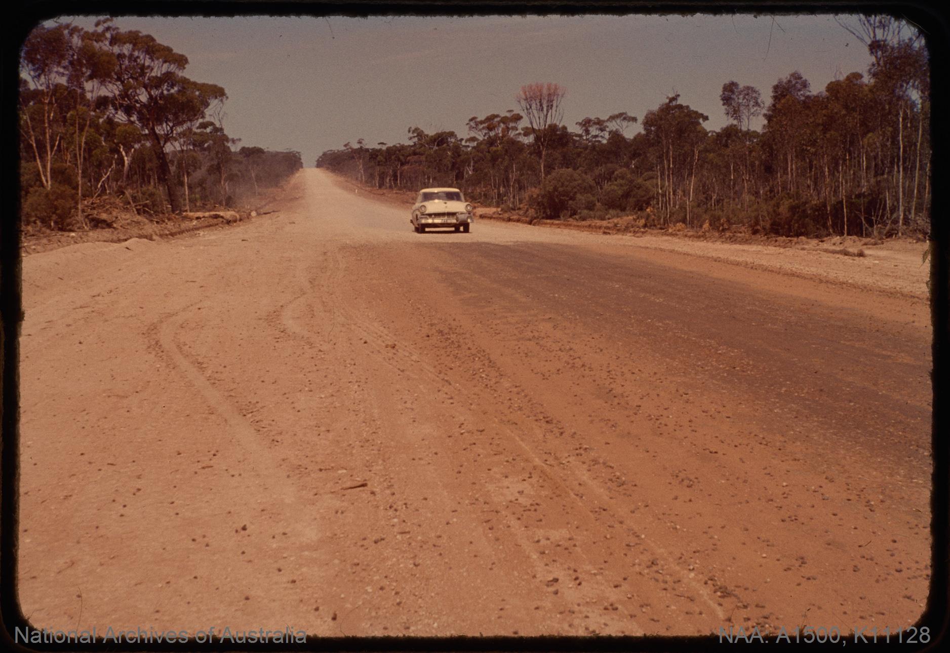A car driving on the dirt road of Eyre Highway in 1964, before the route was fully sealed