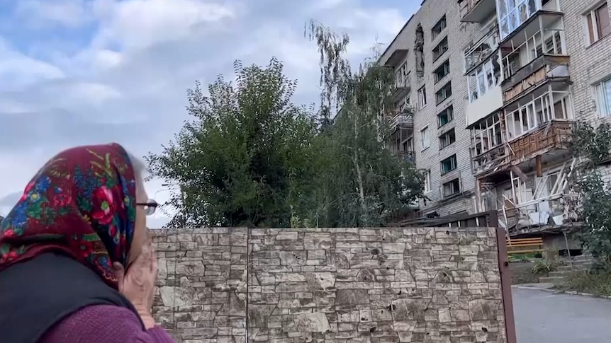 A woman looks at a destroyed building