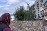 A woman looks at a destroyed building