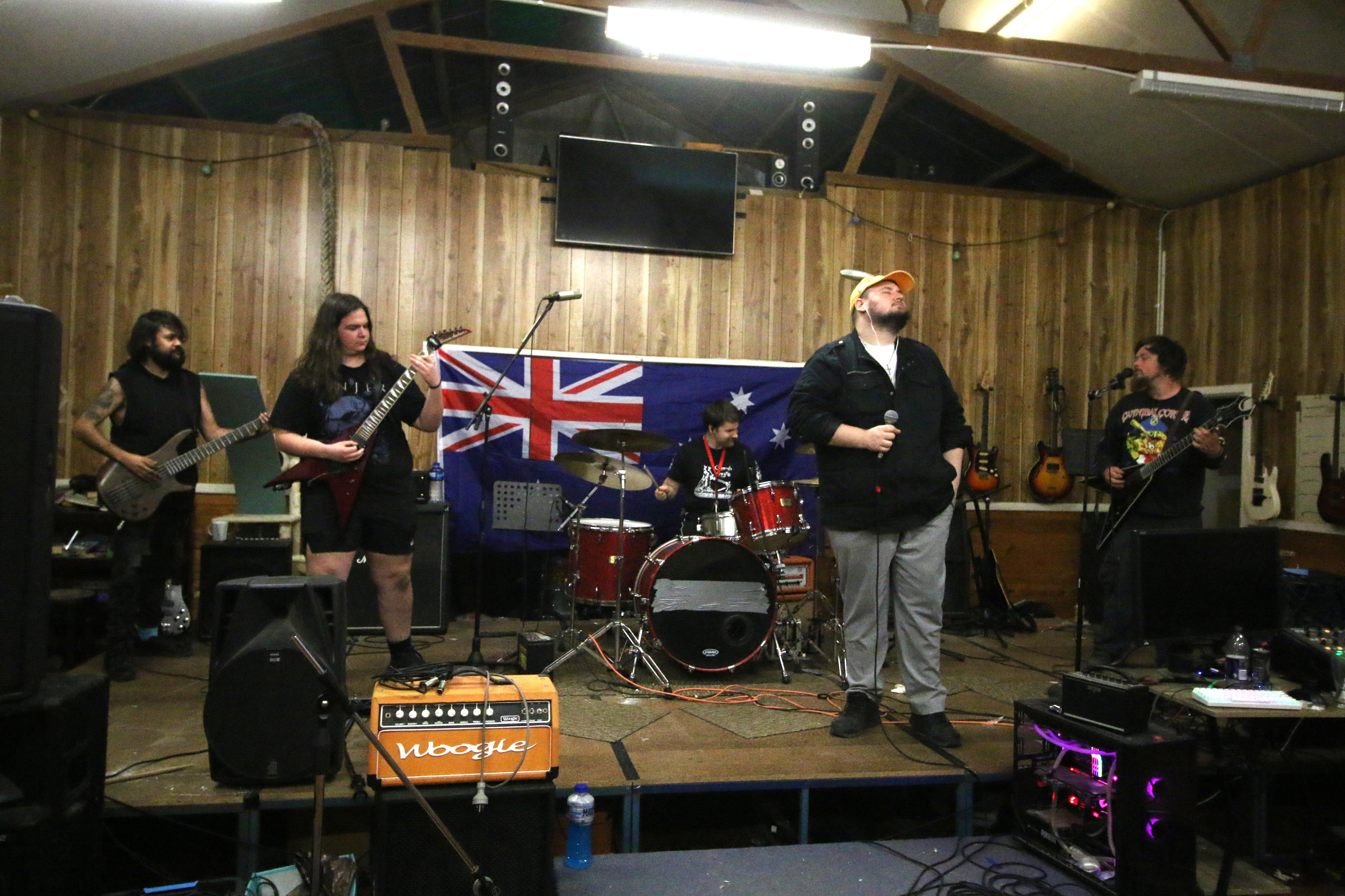 Uma banda de heavy metal toca no palco de um antigo salão comunitário.