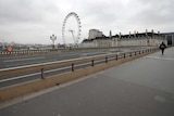 A man walks alone across a bridge overlooking London's big ferris wheel.