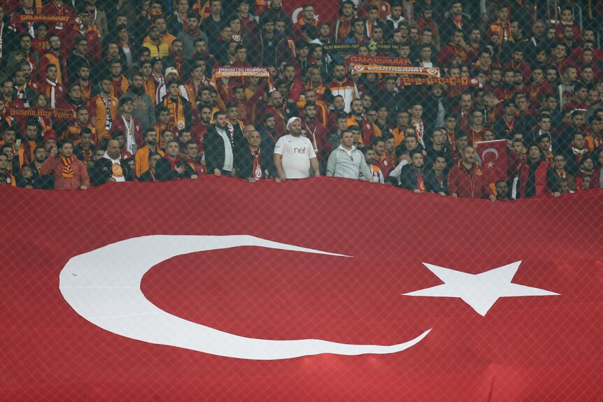 Football fans from Turkey hold up a giant national flag during a match