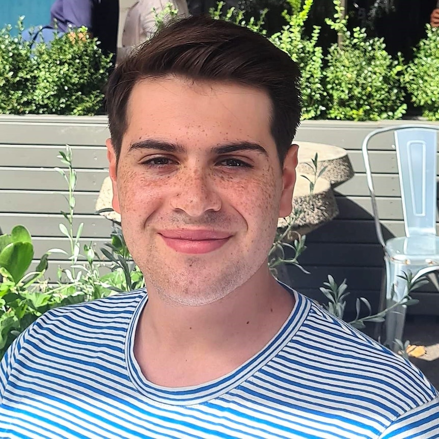 A young man smiles at the camera