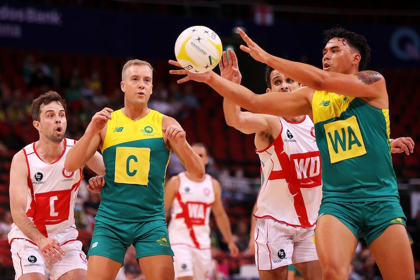 An Australian men's player has his arms out stretched to take a pass, while and England player defends from the side