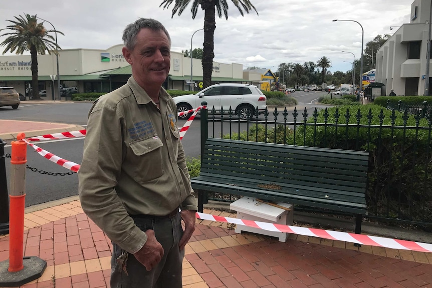 A middle aged man smiles at the camera near a large swarm of bees on Tamworth's main street.