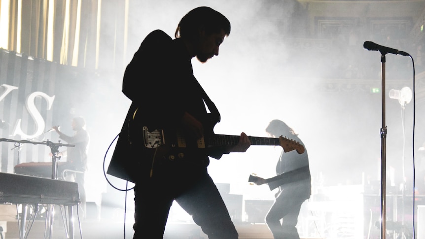 Arctic Monkeys performing at Royal Albert Hall, Alex Turner in silhouette