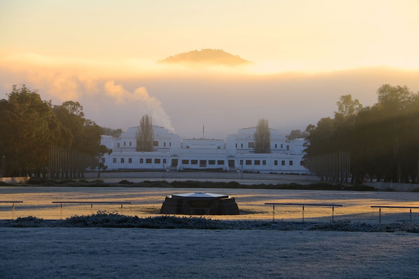 The top of Mount Ainslie pokes its head above the fog behind Old Parliament House