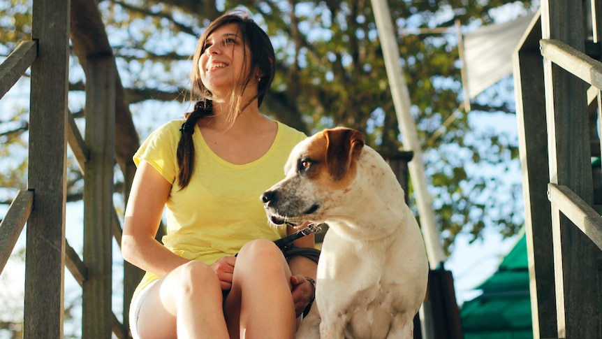 Woman sits next to dog on step