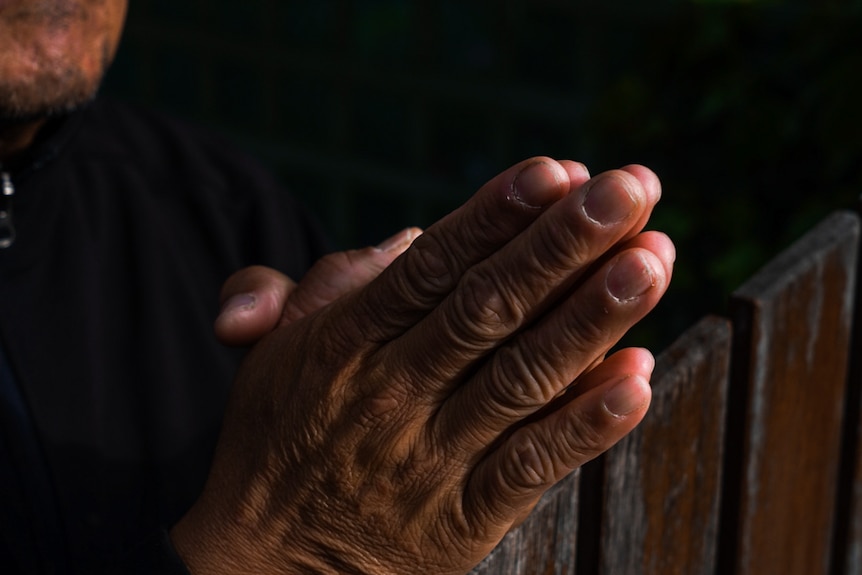 Image of a man's hands clasped together in prayer.
