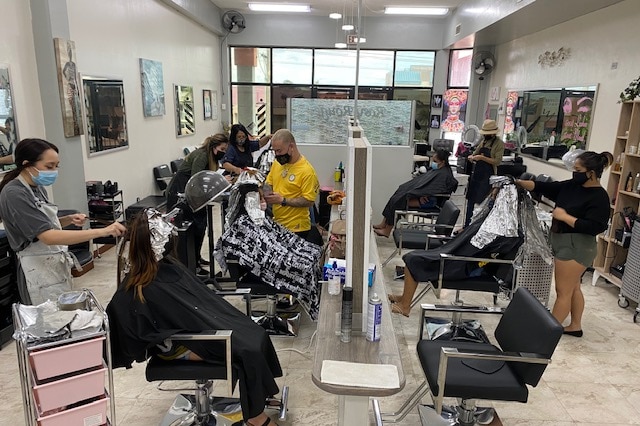 Staff at the Rosy Rouge Hair and Makeup Salon in Guam give haircuts to clients, the staff are all wearing masks.