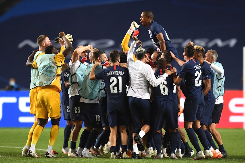 Footballers gather in a group and one player jumps on top of his teammates after a big win.