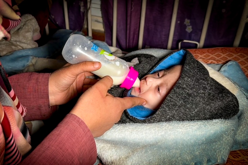 A little girl drinking from a baby bottle 