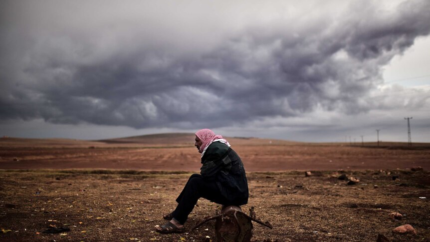 Kurdish man sits near Kobane, border of Turkey and Syria