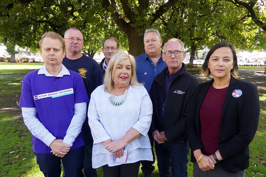 A group of people stand in front of trees.