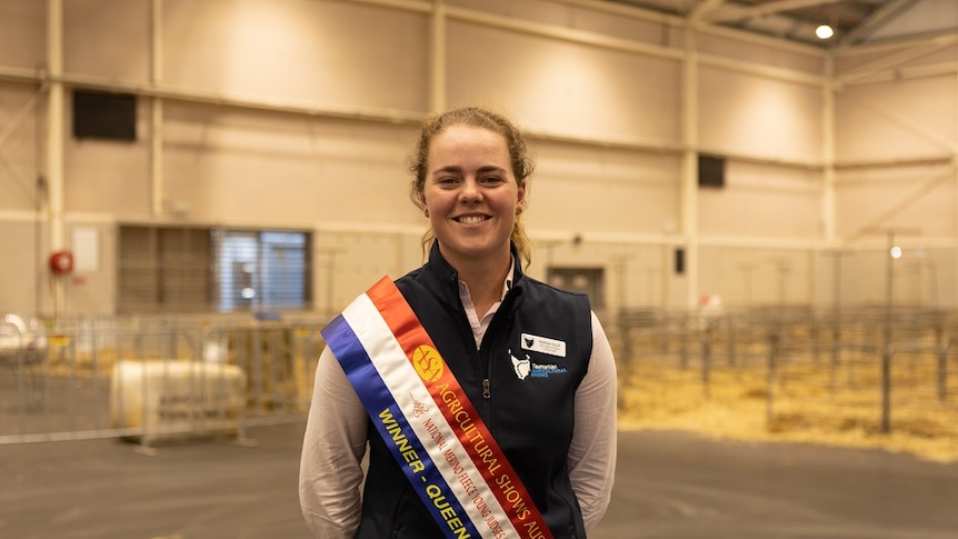 A winner of the Merino Fleece Young Judges Championship at the Sydney Royal Easter Show wearing her winner's sash and smiling