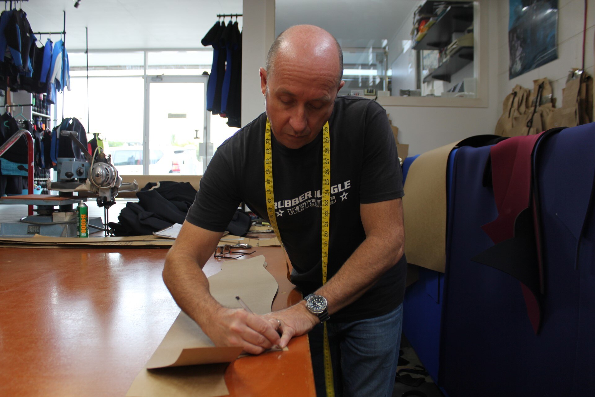 A man measures a length of material on a bench.