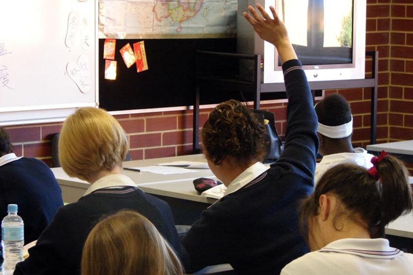 Student with hand up in class.