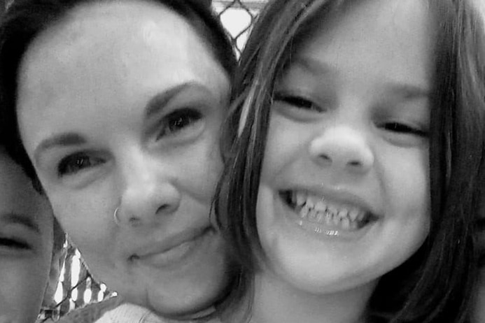 A woman and a young girl smile into the camera.  The photo is in black and white. 