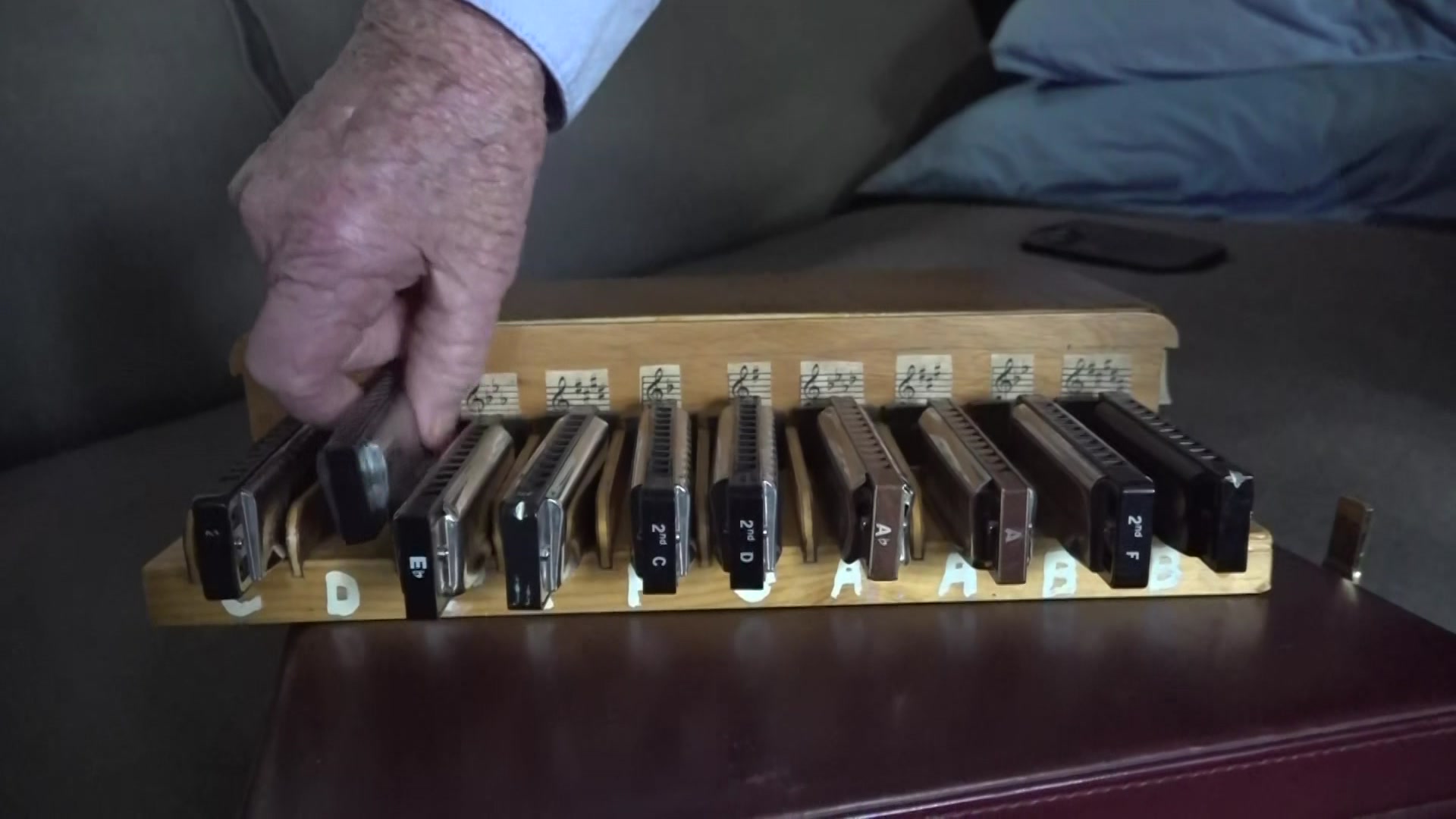 Set of harmonicas with elderly gentleman's hand returning one to the set