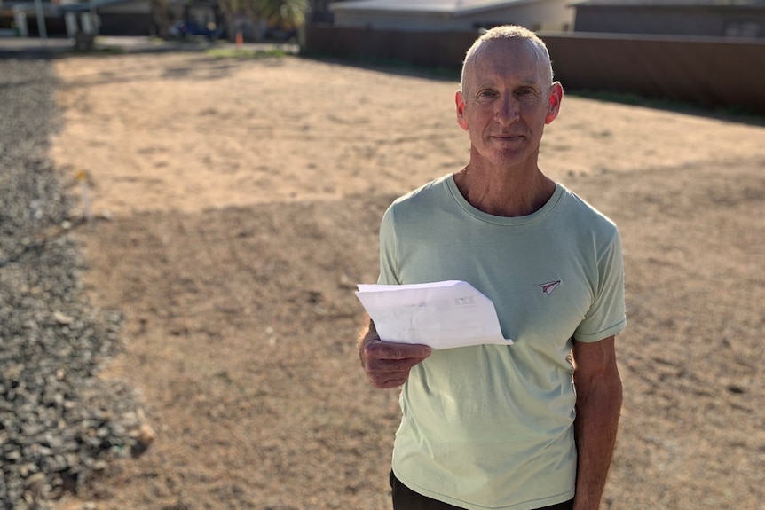 Man in green shirt holds pieces of paper