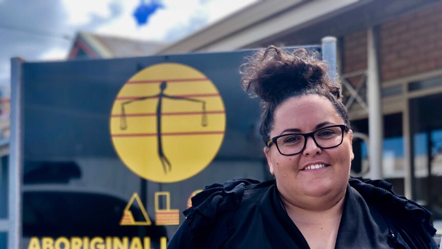 Geraldton Aboriginal Legal Service managing lawyer Kate Turtley-Chappel standing in front of a black sign.