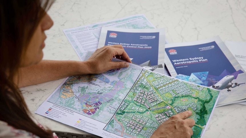 A woman sits at a table, looking at a map