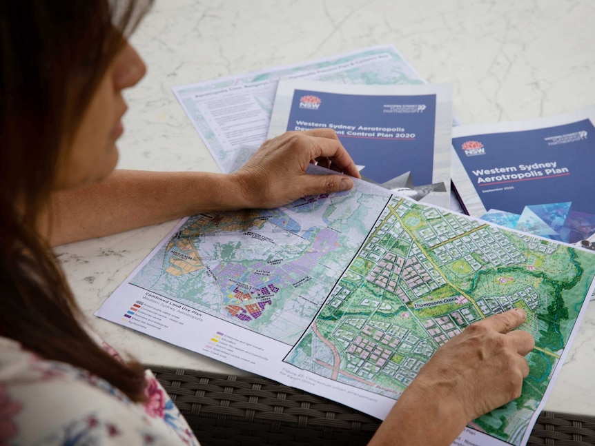 A woman sits at a table, looking at a map