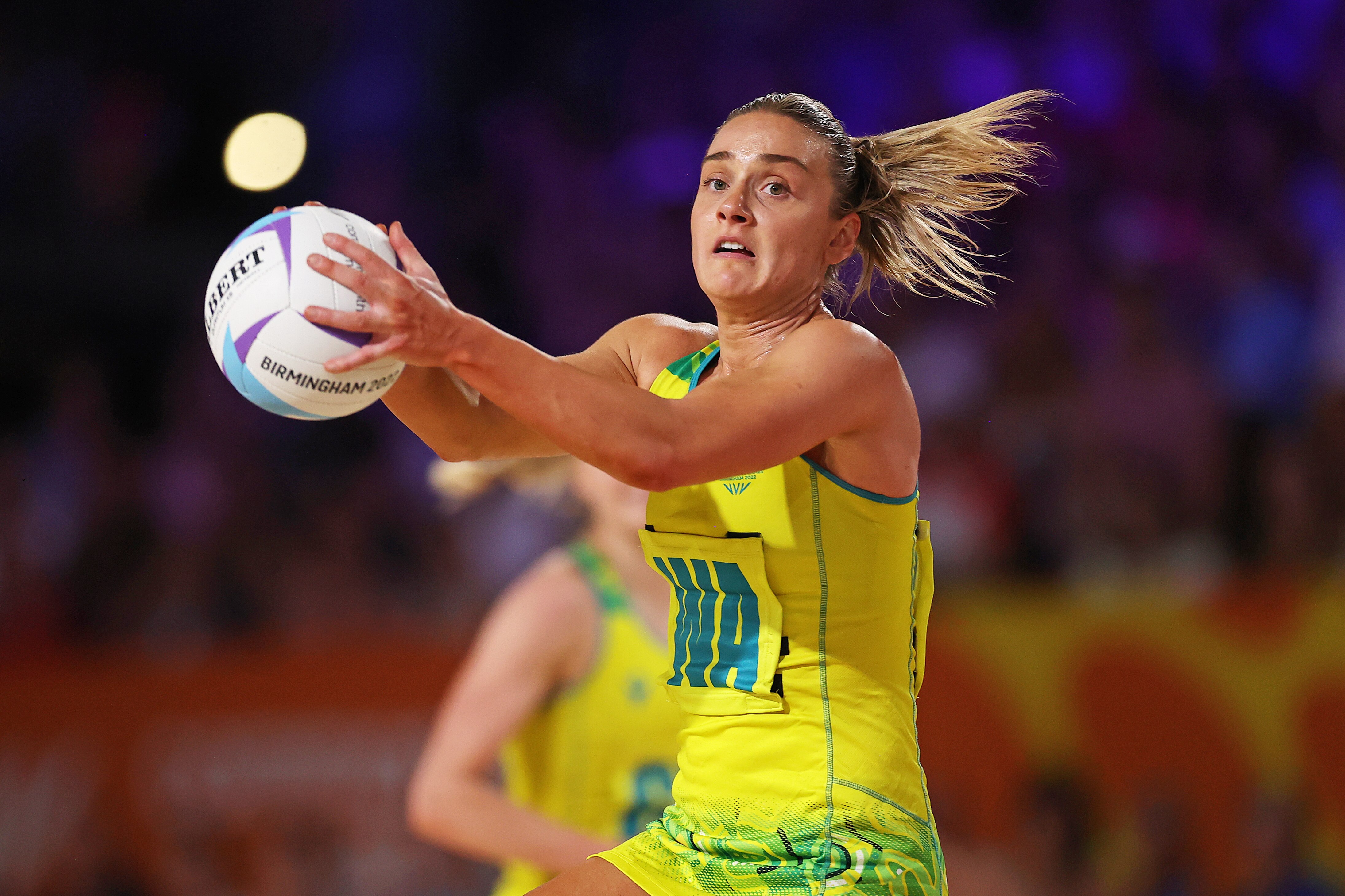 An Australian netball player holds the ball in both hands against England.
