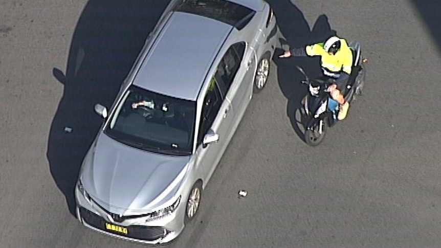 aerial vision of a car and a man next to the back passenger window