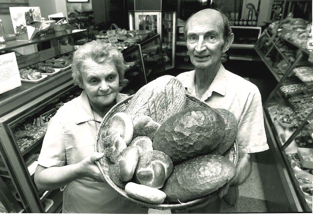 Black and white image of man and woman stand with bread basket.