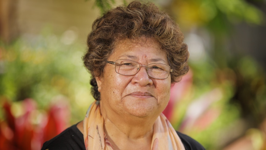 A woman wearing a black top and an orange scarf.