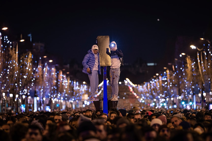 Thousands of revellers packing the street watch a sound and light show projected on the Arc de Triomphe.