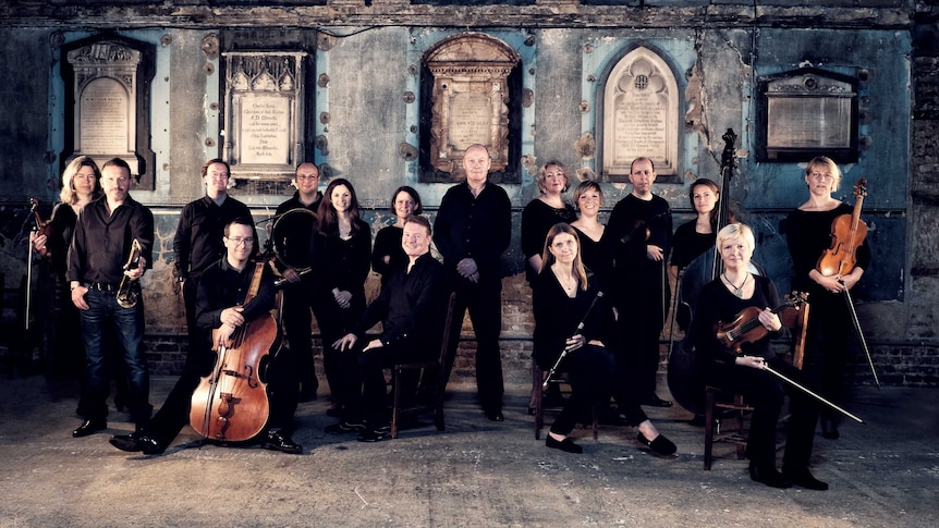 Members of the Gabrieli Consort and Players and their comductor Paul McCreesh dressed in black inside an old chapel