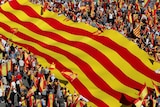 People holding Spanish flags march alongside a giant flag in Barcelona.