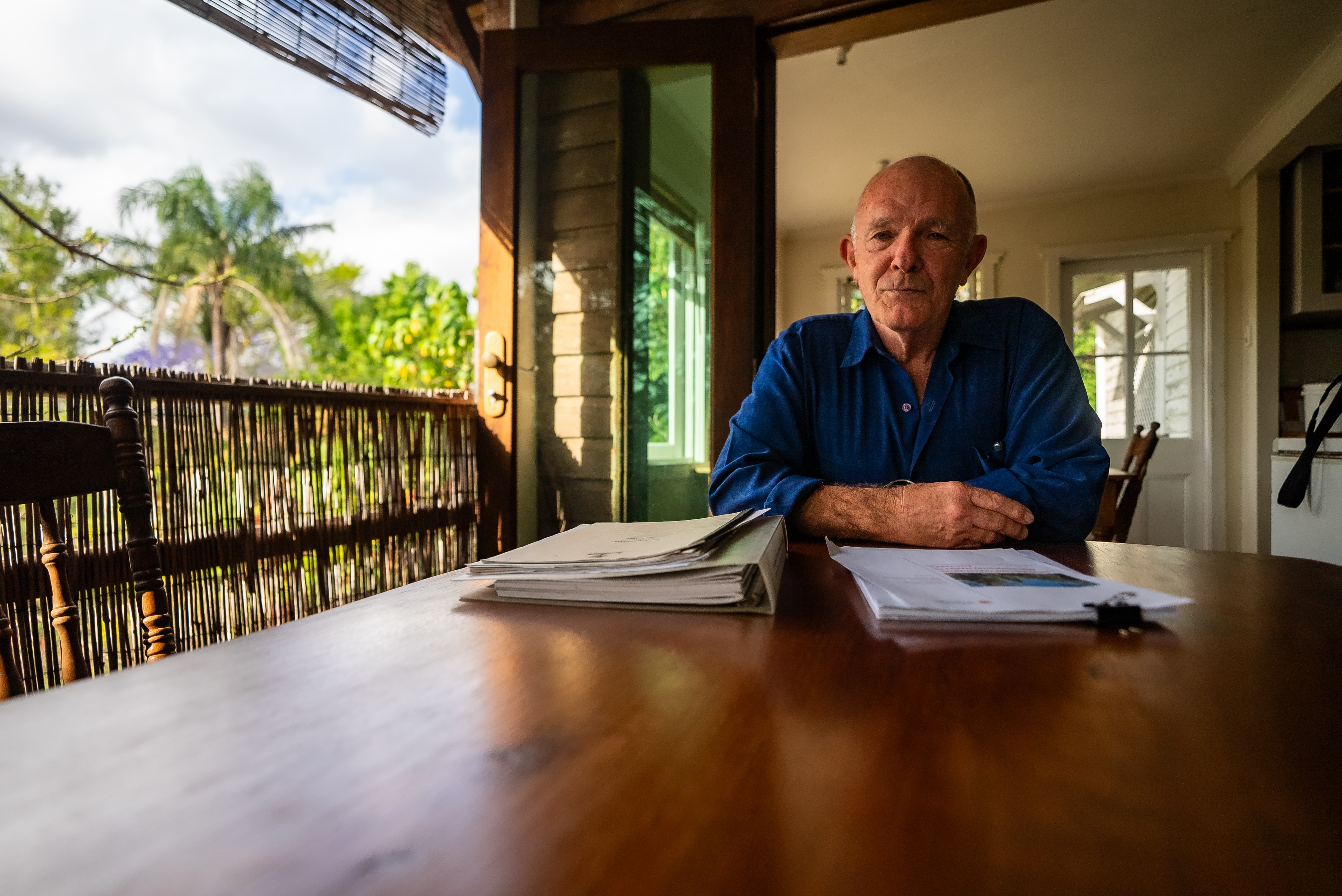 Um homem de camisa azul escura está sentado a uma mesa de madeira, com um relatório impresso à sua frente.