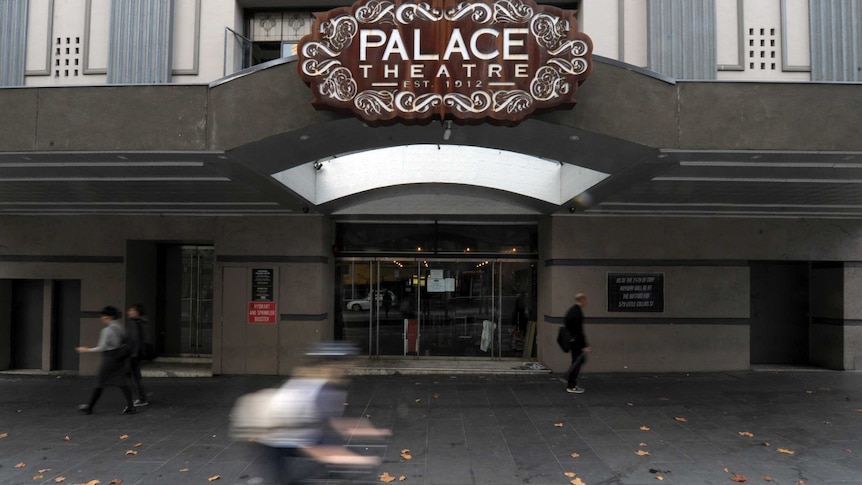 Cyclist rides past the Palace Theatre in Melbourne