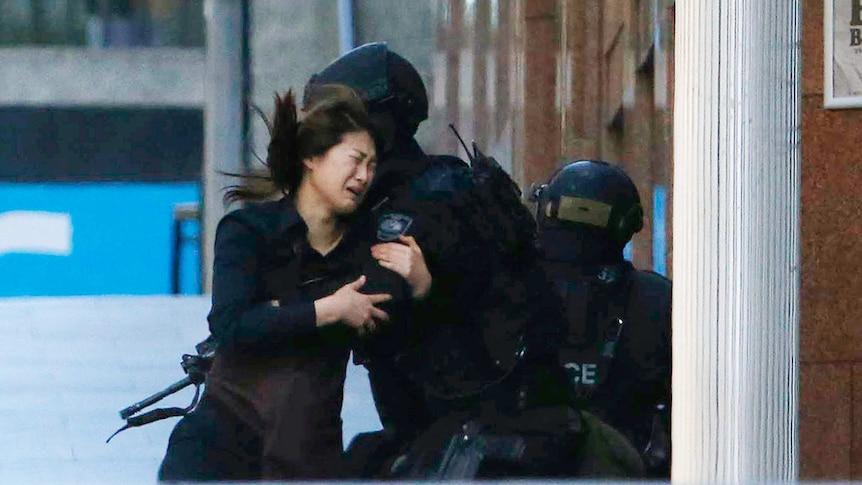 Hostage Jieun Bae runs into the arms of a police officer after fleeing the Lindt cafe.