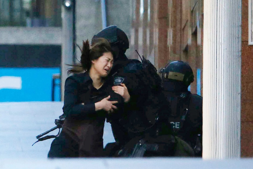 Hostage Jieun Bae runs into the arms of a police officer after fleeing the Lindt cafe.