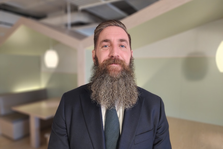 A close of of a man with a long beard smiling. 