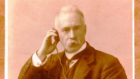 Black and white phone of man holding old radio