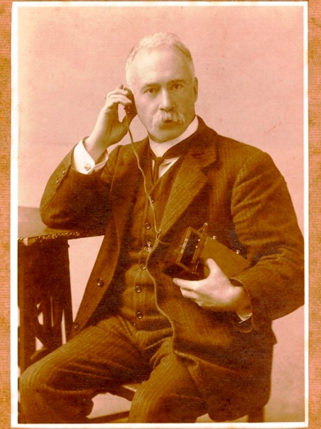 Black and white phone of man holding old radio