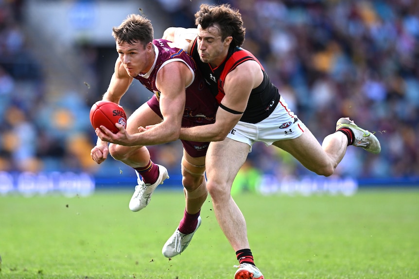 Seorang pemain AFL Brisbane Lions mencoba melakukan handball saat di-tackle oleh lawan Essendon.