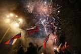 Pro-Russian activists wave flags in the street as fireworks explode in the sky