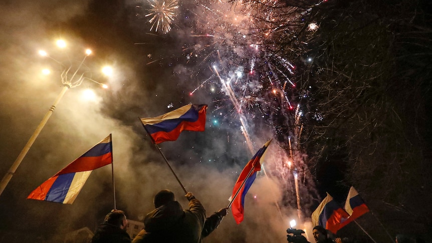 Pro-Russian activists wave flags in the street as fireworks explode in the sky